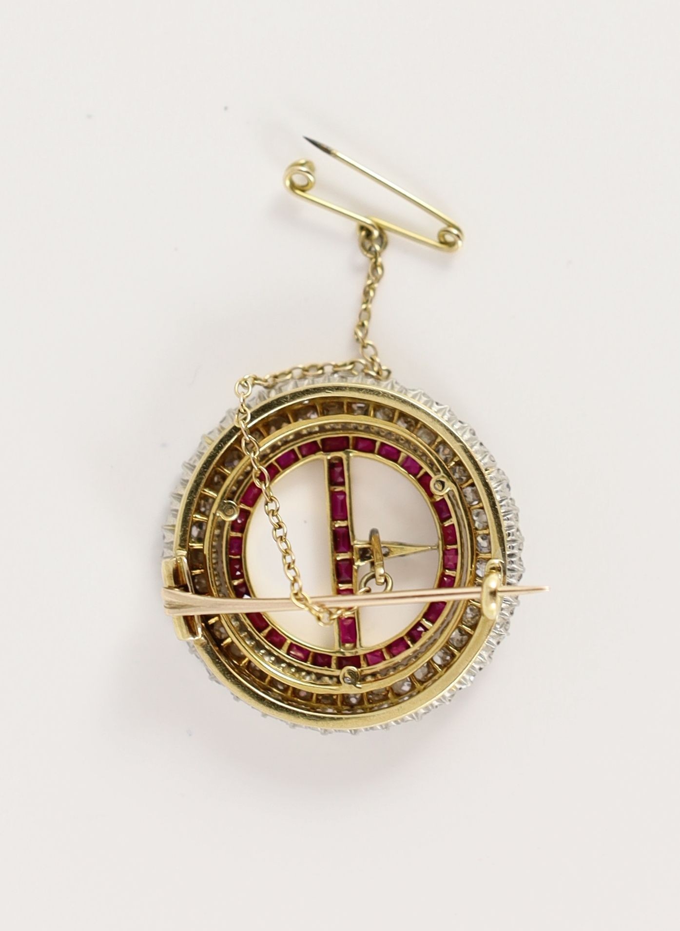 A 20th century gold and platinum, ruby and diamond set openwork circular 'buckle' brooch